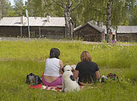 Bild på Ångermanlandsgården, folk sitter i gräset
